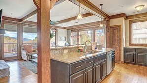 A spacious kitchen with dark cabinetry, granite countertops, and a large island. There is a sliding glass door leading to an outdoor patio area.