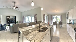 A spacious kitchen with a marble countertop, stainless steel appliances, and a dining area with a sofa and table.