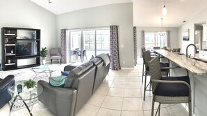 A spacious living area with a sofa, TV, and a dining area with chairs.