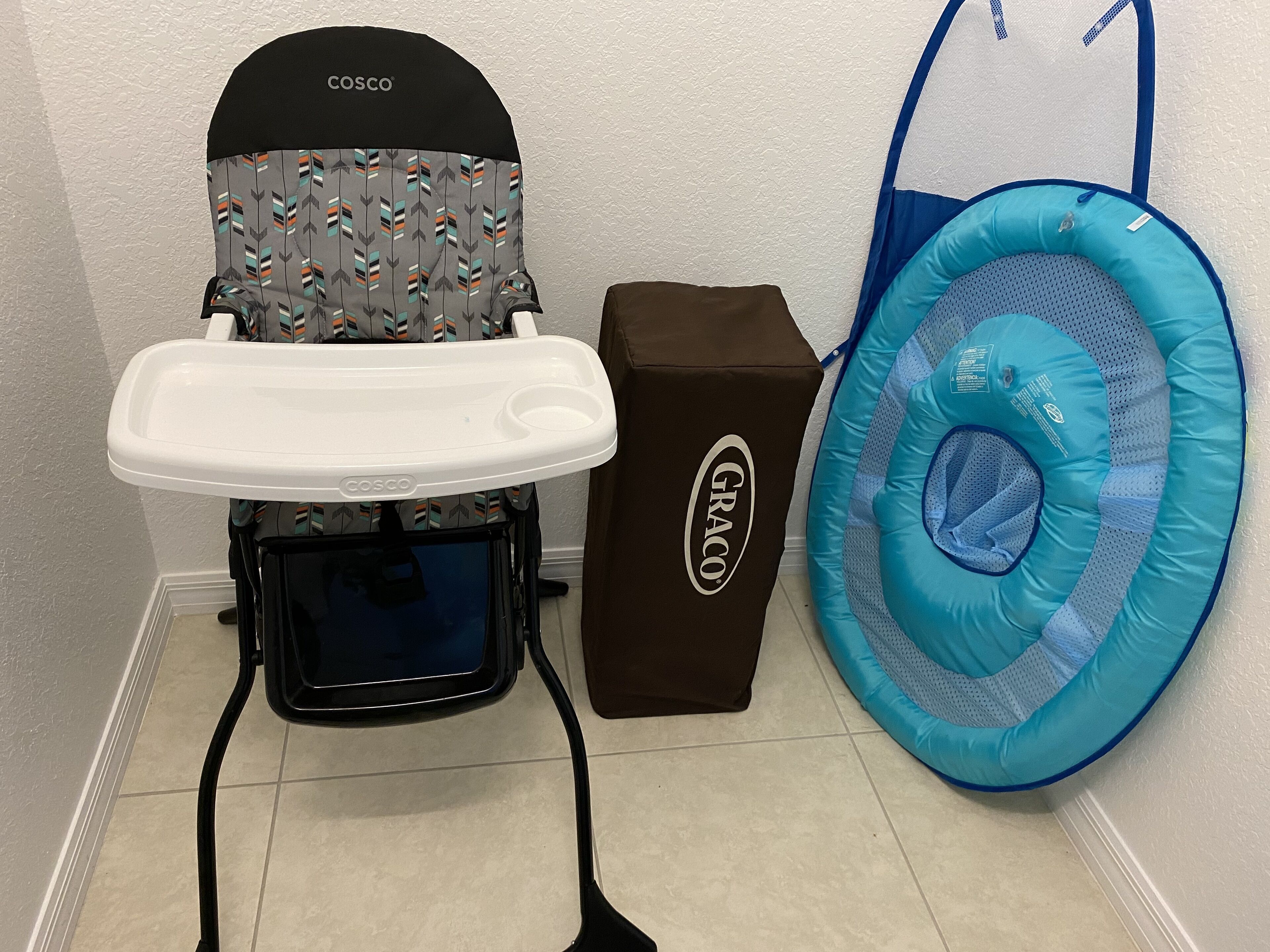 A baby changing station with a COSCO brand changing table, a GRACO brand booster seat, and a blue inflatable ring.