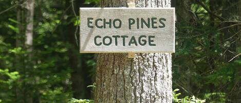 Un letrero en un árbol que dice 'Echo Pines Cottage'.