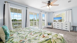 Una camera da letto con un letto grande, una ventola a soffitto, un comò e vista sull'esterno.
