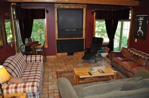 A cozy living room with a television, two sofas, a coffee table, and a fireplace.