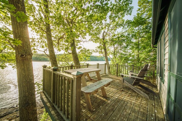 A wooden deck with a picnic table and chairs overlooking a lake.