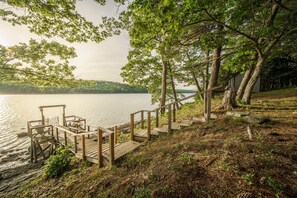 A wooden dock extending into a lake, surrounded by trees and a grassy area.