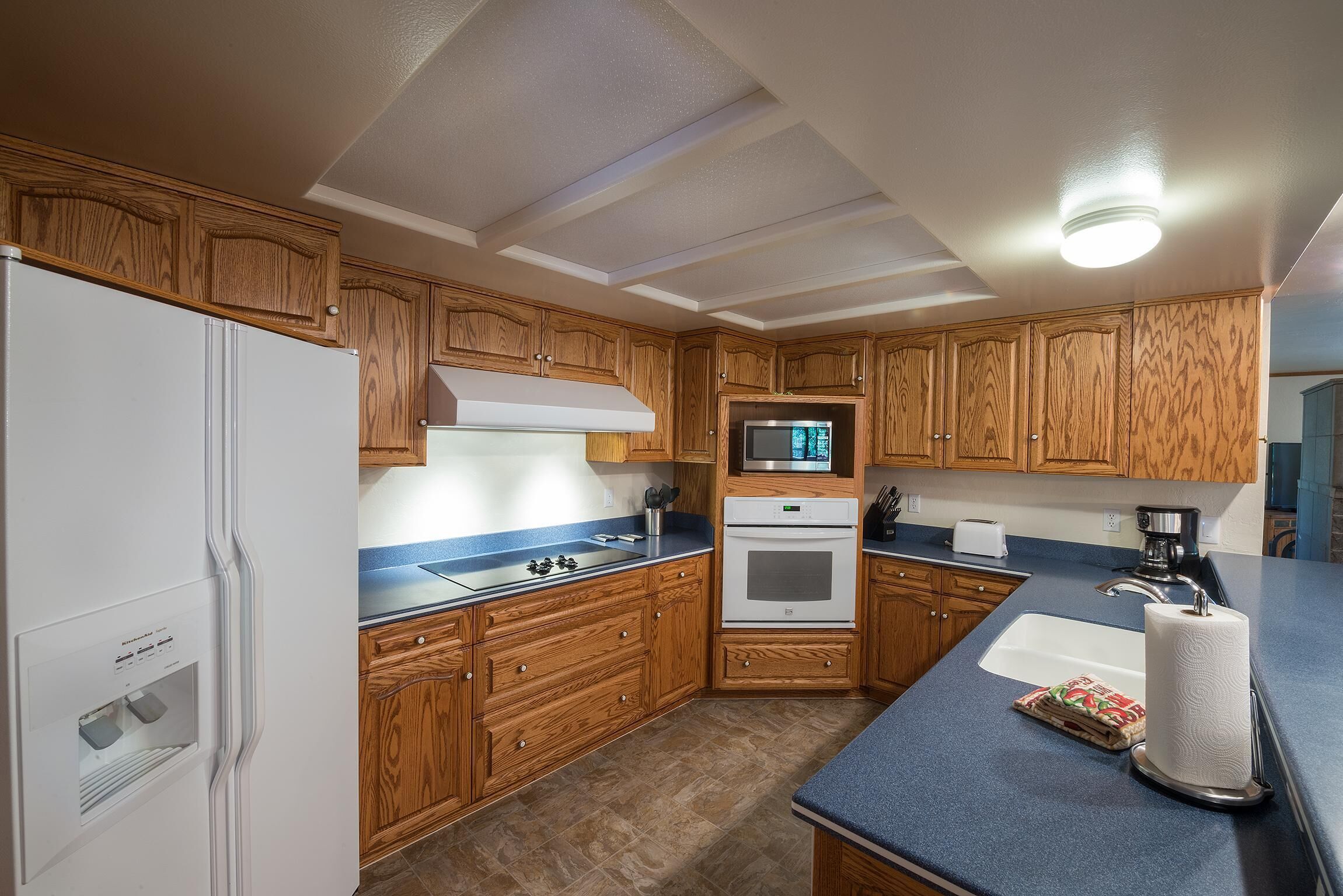 A compact kitchen with wooden cabinets, a built-in microwave, a stove, and a sink.