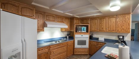 A compact kitchen with wooden cabinets, a built-in microwave, a stove, and a sink.