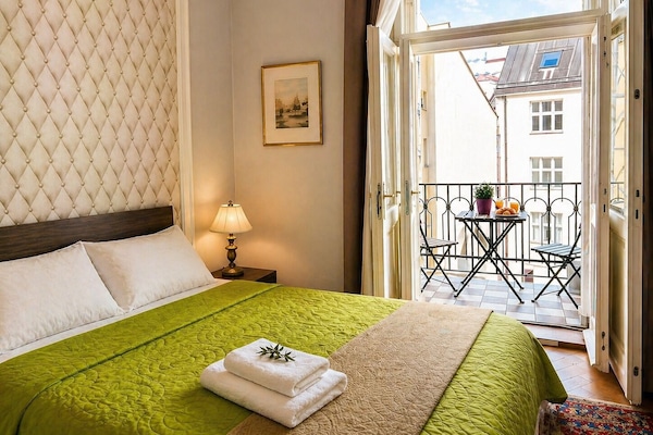 Bright bedroom with balcony breakfast, green bedding and quiet courtyard view.