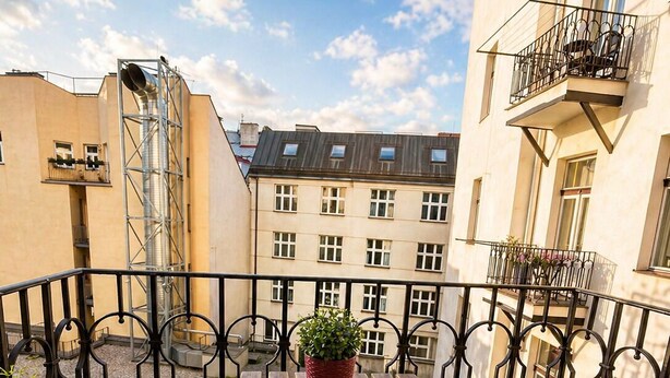 Ein Balkon mit Tisch, Stühlen, einer Topfpflanze und einem Croissant.