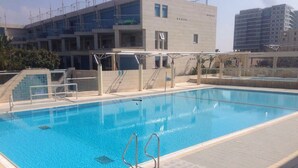 A swimming pool with a clear blue water surface, surrounded by a tiled deck. - 0cean front Herzelia condo next to beach and resturants (Herzliya)