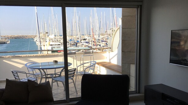 A modern living room with a large sliding glass door leading to a marina view. - 0cean front Herzelia condo next to beach and resturants (Herzliya)