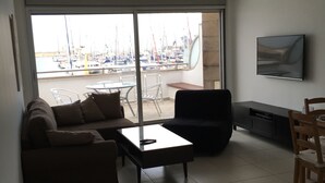 A modern living room with a sofa, coffee table, and a TV mounted on the wall. - 0cean front Herzelia condo next to beach and resturants (Herzliya)