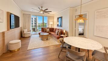 A modern living room with a sofa, coffee table, and chairs, a balcony with a view, and a ceiling fan.