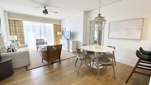 Een ruime woonkamer met een eethoek, een televisie en een plafondventilator.