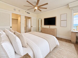 A bedroom with a large bed, a ceiling fan, a TV, a dresser, and a view of the sea. - 1 Bdrm Ocean view Res. Suite w balcony, located at The Ritz, in Key Biscayne (Key Biscayne)