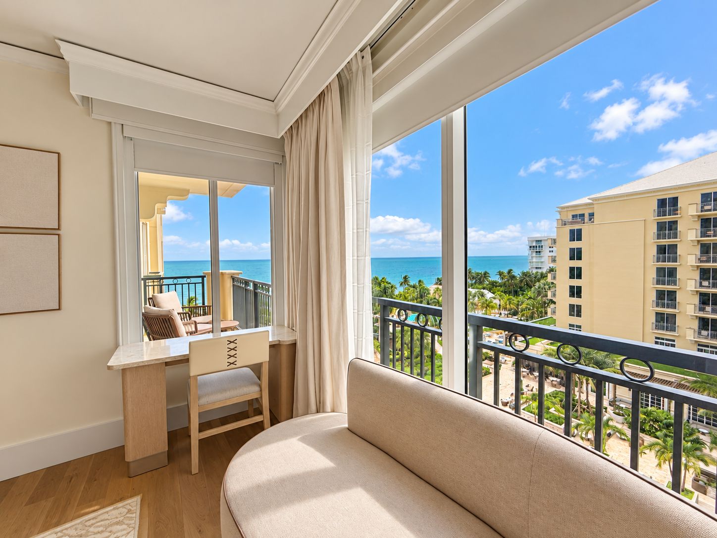Une chambre d’hôtel avec un balcon, un bureau, une chaise et un canapé.