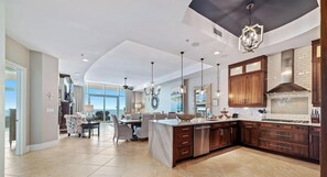 A spacious kitchen with wooden cabinets, a central island, and pendant lighting.