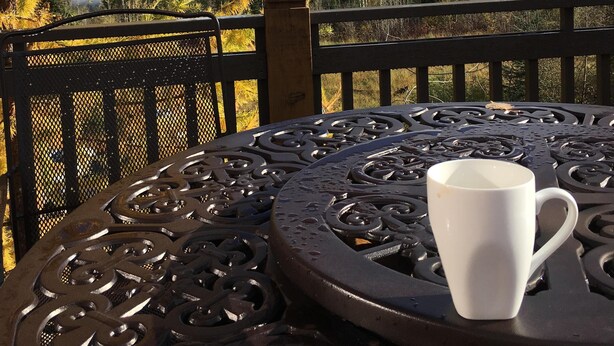 A table with a white cup, surrounded by a metal fence with a mountain view in the background. - Spectacular Top Floor 2 Br W/ Hot Tub and Panoramic View (Golden)