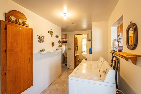 A laundry room with a washing machine, wooden door, and decorative wall items.