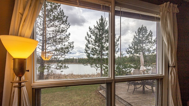 A room with a large window offering a view of a lake and trees. - Private Lodge on Private Lake, Embarrass MN. Boat & Motor Cable WiFi Internet  (Embarrass)