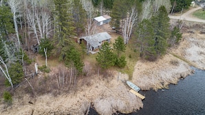 An aerial view of a cabin surrounded by dense forest, with a dock extending into a body of water. - Private Lodge on Private Lake, Embarrass MN. Boat & Motor Cable WiFi Internet  (Embarrass)