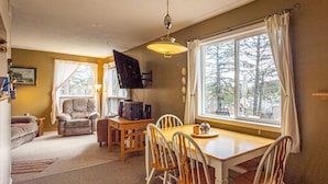A cozy living room with a sofa, a dining table with chairs, a TV, and a large window with curtains. - Private Lodge on Private Lake, Embarrass MN. Boat & Motor Cable WiFi Internet  (Embarrass)