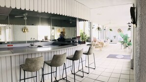 A modern kitchen with a bar area, white cabinetry, and a large mirror. - Beautiful Condo at Madeira Beach, 2Htd Pools,Walk to Beach,WiFi,Piers,Johns Pass (Madeira Beach)