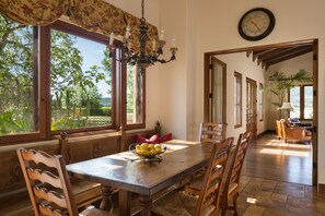 Un coin repas avec une table en bois, des chaises, un lustre et une horloge au mur.