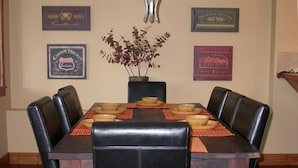 Un coin repas avec une table rectangulaire dressée pour quatre personnes, entourée de chaises en cuir noir.