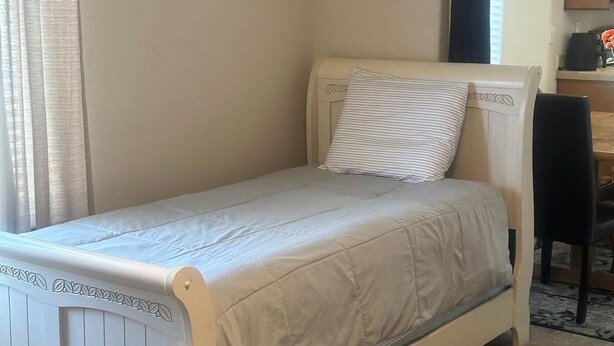 A single bed with a headboard, a bedside table, and a chair in a room with a carpeted floor. - Panoramic Cliffs Retreat (Hatch)