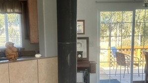 Une cuisine avec un poêle à bois noir, un sol carrelé et une fenêtre avec des stores.