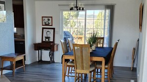 Un grand espace dédié à la salle à manger, avec une table et des chaises en bois, une machine à coudre et des tableaux encadrés accrochés au mur.