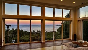 A room with large windows, a telescope, and a view of the ocean. - China Mountain House - Ocean Views & Modern Design (Port Orford)