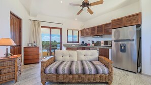 Ein Zimmer mit Bett, Küchenzeile und Blick ins Freie.