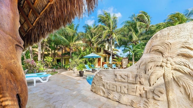 Ein Steinh relief mit der Aufschrift 'ISLA RETREATS', einem Pool, Liegestühlen und Palmen.