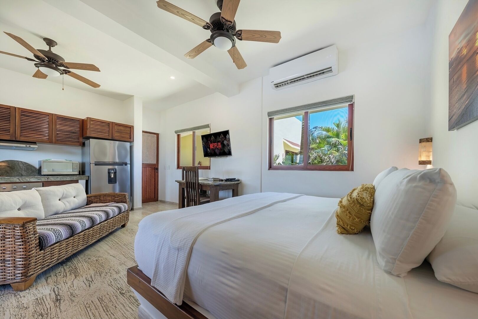 Un dormitorio con cama, televisor, ventilador de techo, equipo de aire acondicionado y ventana con vista.