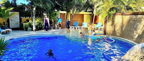 A swimming pool surrounded by palm trees and lounge chairs.