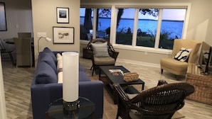 Ein Wohnzimmer mit Sofa, Sesseln, einem Couchtisch und Blick aufs Wasser.