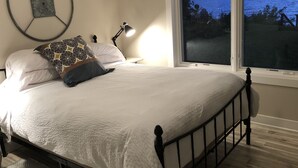 Ein ordentlich bezogenes Bett mit weißer Decke, einer runden Wanddekoration und einem Nachttisch mit Lampe.