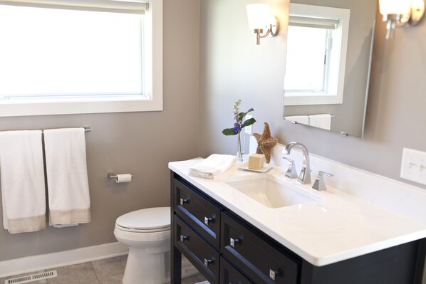 A modern bathroom with a white sink, dark cabinetry, and a large mirror.