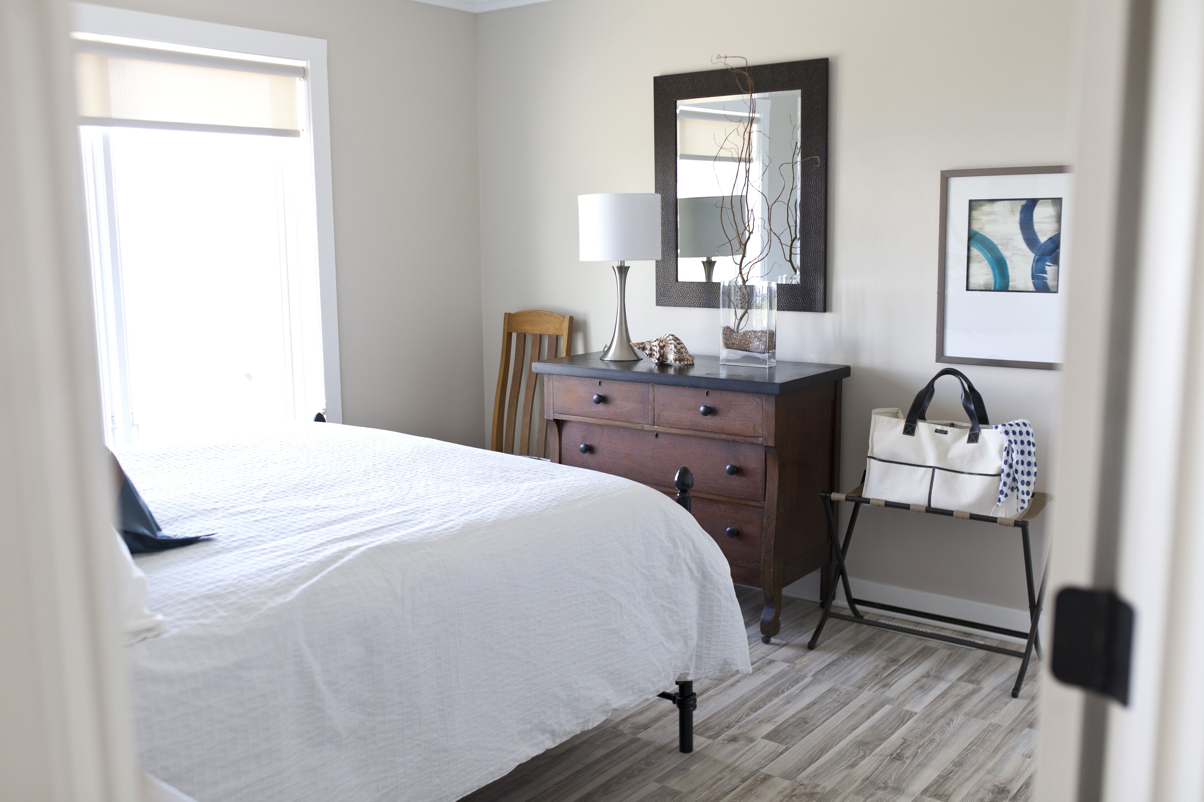 Un dormitorio con cama, cómoda, espejo y obras de arte.