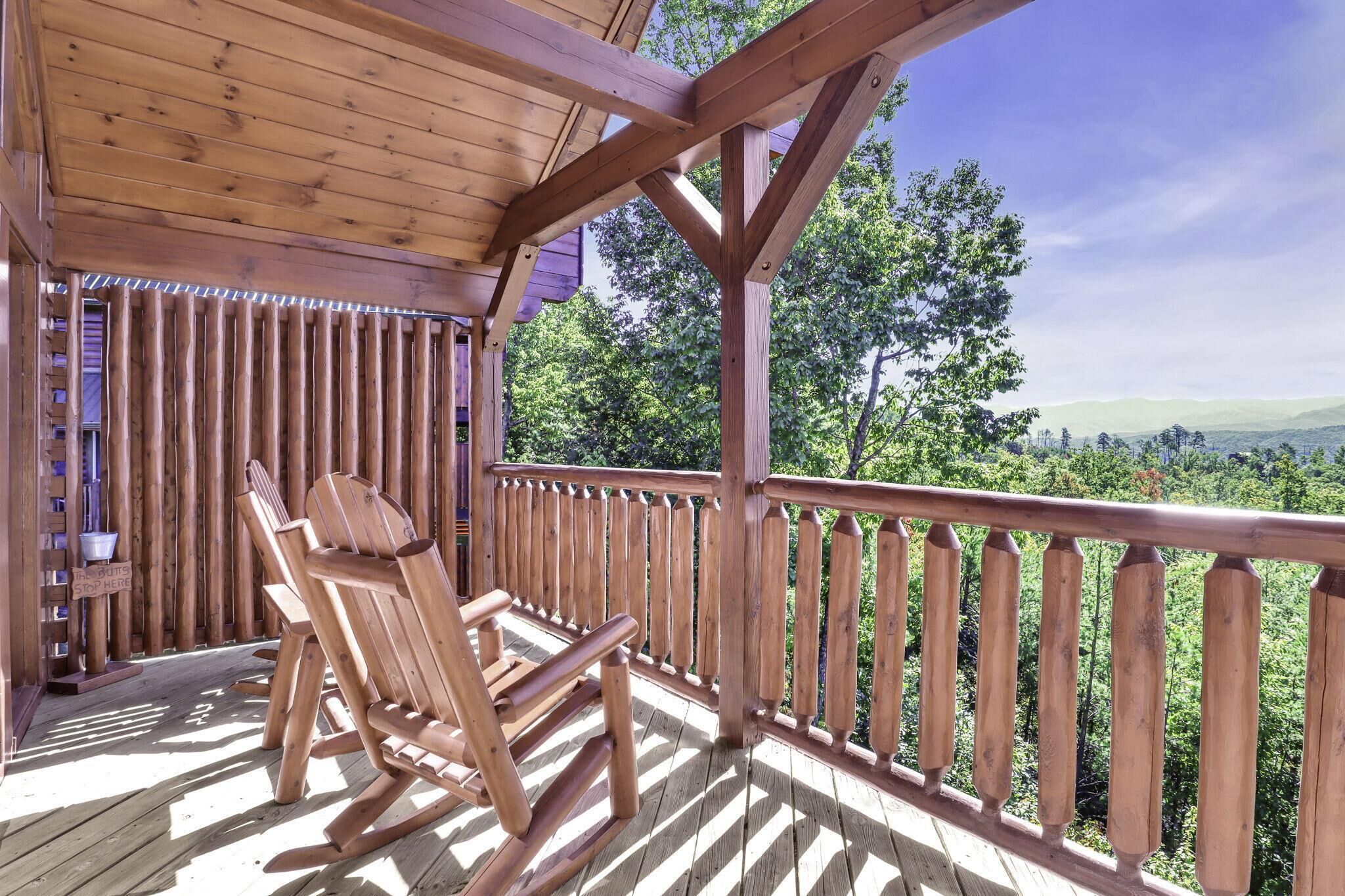 Eine Holzterrasse mit einem Schaukelstuhl und Blick auf eine bewaldete Landschaft.