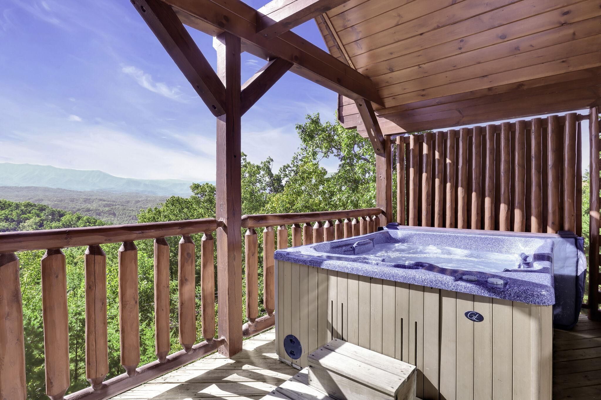 En træterrasse med jacuzzi og udsigt til bjerge.