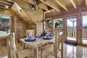 Ein Esszimmer mit Holzboden, einem Tisch für vier Personen, einer Kristallleuchter und Blick ins Freie.