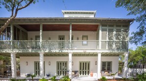Ein zweistöckiges Haus mit Balkon, mehreren Türen und einer Veranda.