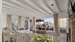 Un salon spacieux comprenant un canapé, une table à manger et des chaises. De grandes fenêtres offrent une vue sur un port de plaisance.