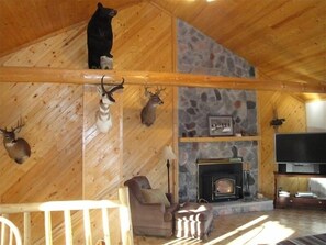 Cozy cabin-style living area with a fireplace, comfortable seating, and a mounted TV.