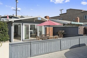A residential property with a covered patio, a barbecue grill, and a fenced backyard.