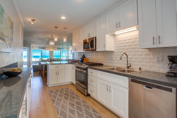 A modern kitchen with white cabinets, stainless steel appliances, and a large island with a sink and stove.