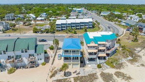 A coastal hotel with multiple floors, a beach view, and a road with vehicles.